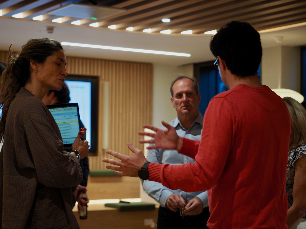Founders and investors in an active working discussion around a laptop at a NoBa event